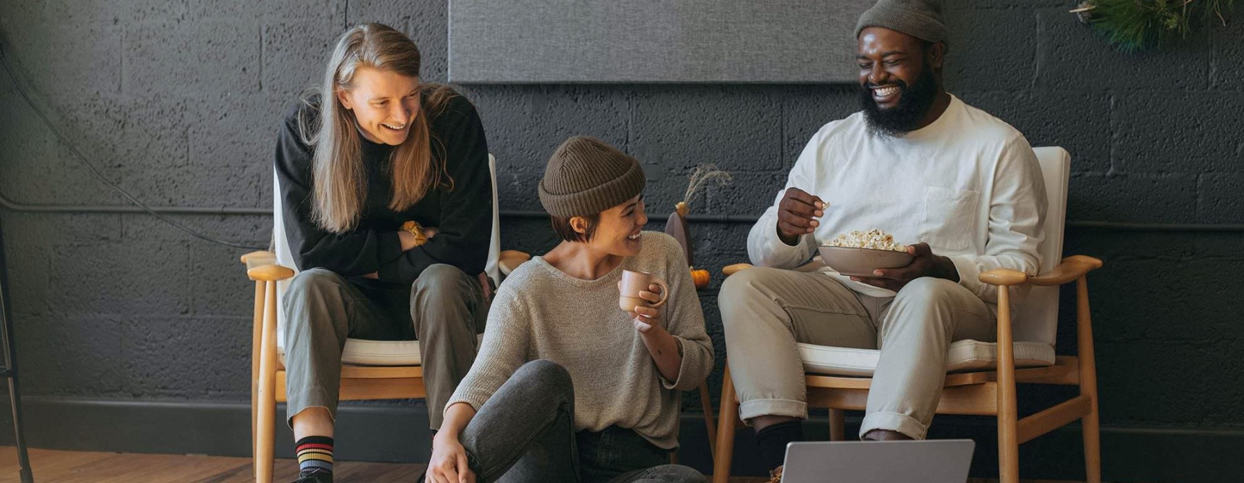 three people laughing and looking at a computer